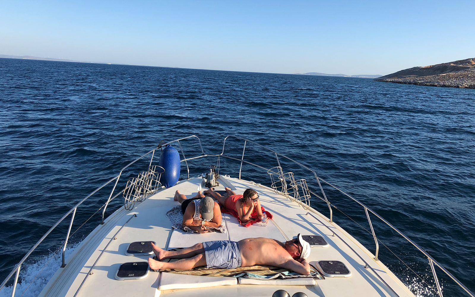 People relaxing on a yacht deck during a daily cruise to Delos and Rhenia islands.