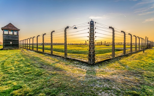 Auschwitz-Birkenau fence and watchtower at sunset during guided tour from Krakow.