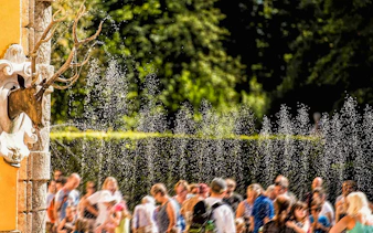 Visitors enjoying water trick fountains at Hellbrunn Palace, Salzburg.