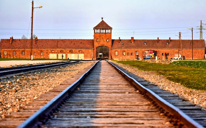 Railway tracks leading to Auschwitz-Birkenau entrance, part of full-day tour with transfers.