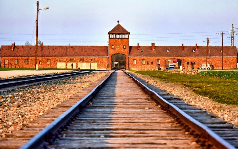 Railway tracks leading to Auschwitz-Birkenau entrance, part of full-day tour with transfers.