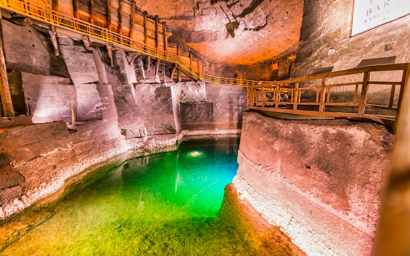 Wieliczka Salt Mine chamber with wooden walkways and illuminated green water.