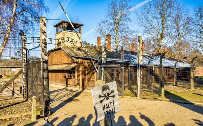 Auschwitz-Birkenau entrance gate with warning sign, part of full-day tour.