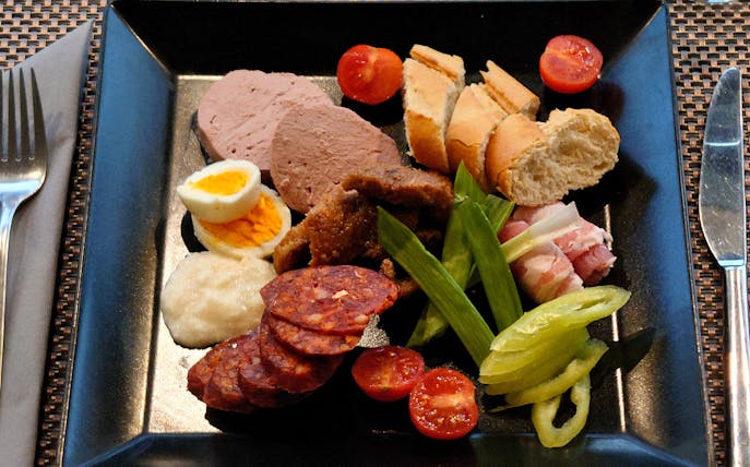 Hungarian brunch platter with meats, bread, and vegetables on Budapest sightseeing cruise.