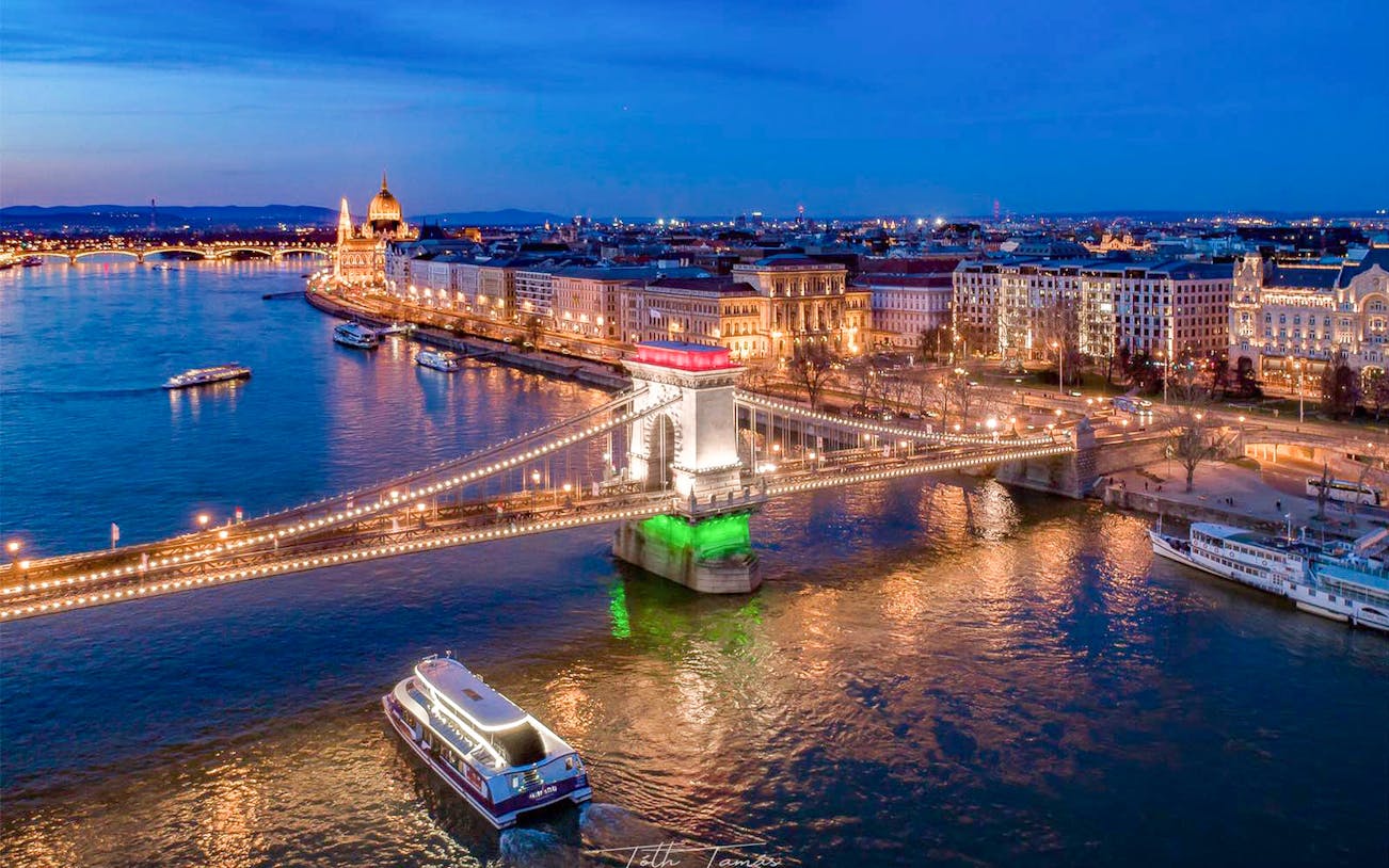 Sightseeing cruise on the Danube River near Budapest's Chain Bridge at dusk.
