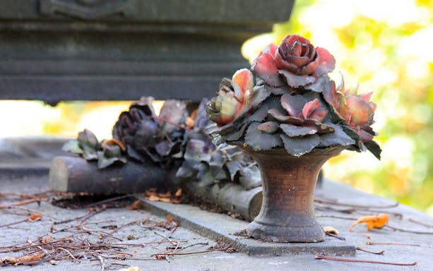 Stone grave adorned with floral sculpture at Père Lachaise Cemetery.