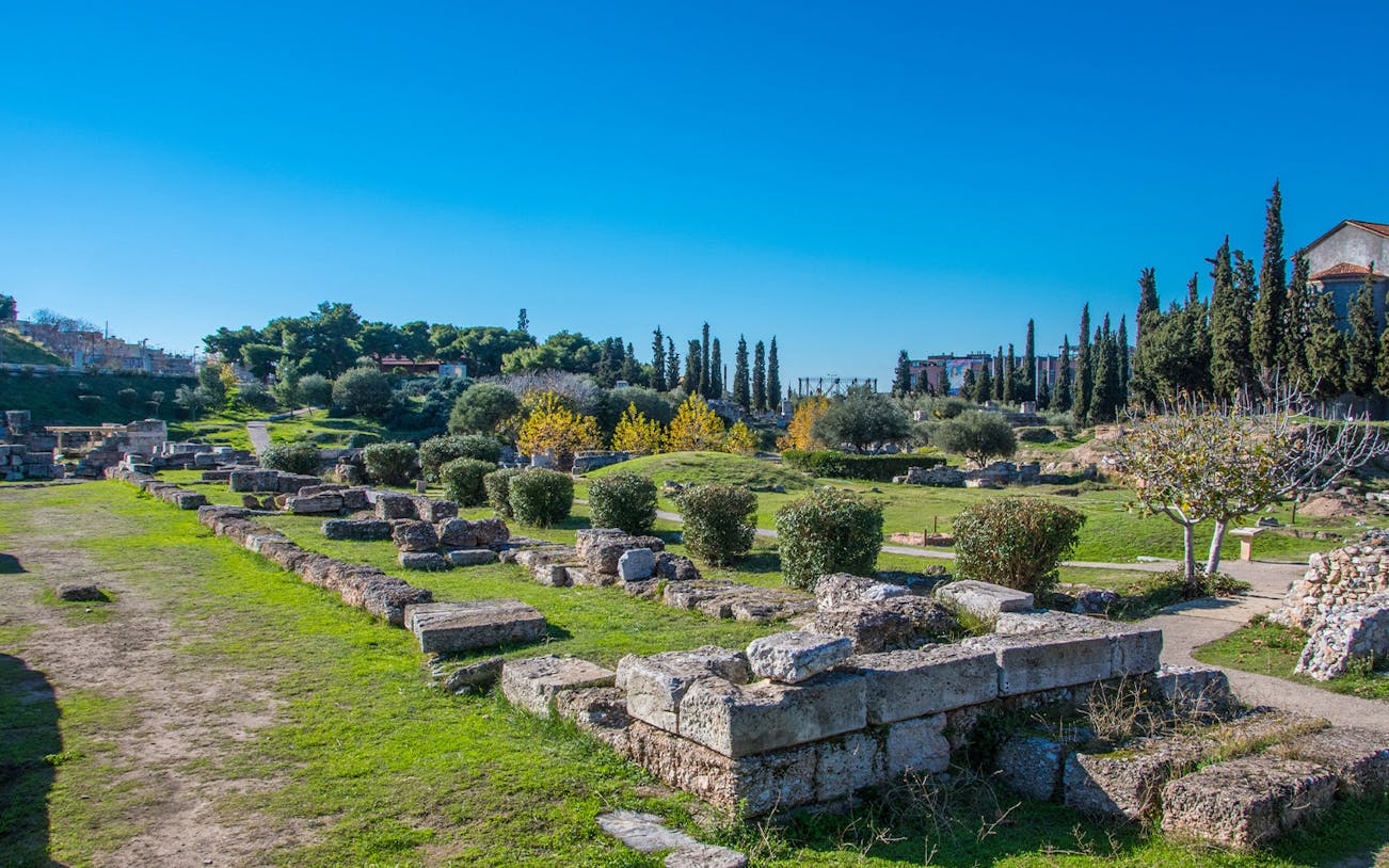 Ancient ruins of Kerameikos in Athens with greenery and clear blue sky.