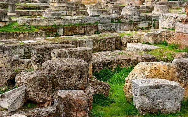 Ancient ruins of Kerameikos in Athens with stone blocks and greenery.