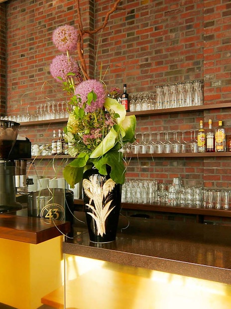 Bar area at Panoramapunkt Berlin with coffee machine and floral arrangement.