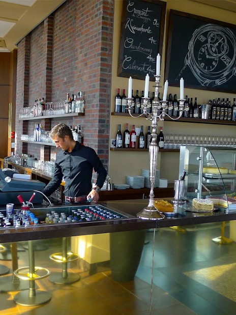 Cafe interior at Panoramapunkt Berlin with staff preparing drinks and desserts on display.