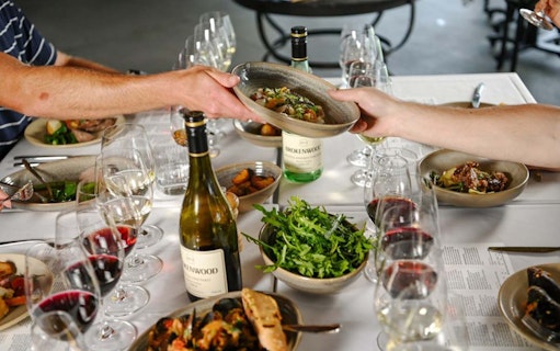 Wine tasting and dining experience at Brokenwood Winery with shared dishes and glasses of wine.