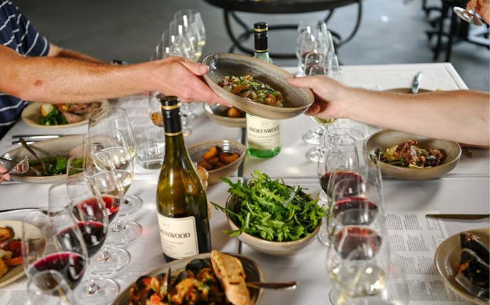 Wine tasting and dining experience at Brokenwood Winery with shared dishes and glasses of wine.