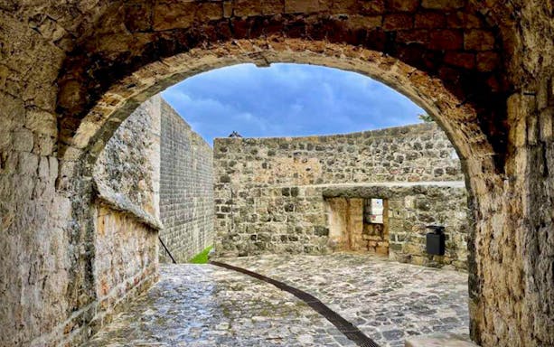 Dubrovnik City Walls archway with stone pathway and sky view.