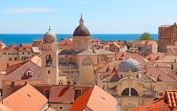 Dubrovnik cityscape with historic walls and red rooftops overlooking the Adriatic Sea.