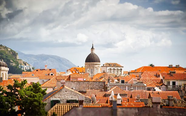Dubrovnik cityscape with historic orange rooftops and dome, ideal for early bird or sunset tours.