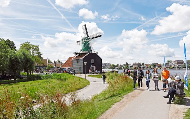 Windmill and visitors at Zaanse Schans, Netherlands, on a sunny day.