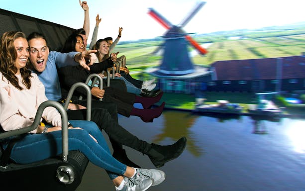 People enjoying a ride with a view of a windmill at Zaanse Schans during the Floriade Expo tour from Amsterdam.