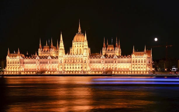 Hungarian Parliament illuminated at night, viewed from across the Danube River.