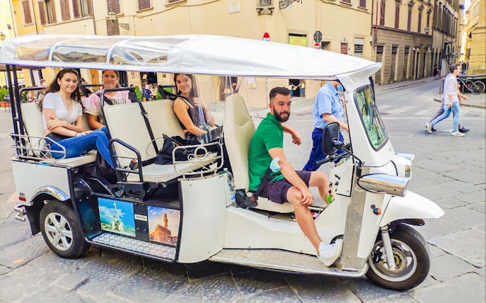 Electric golf cart tour in Florence with passengers exploring city streets.