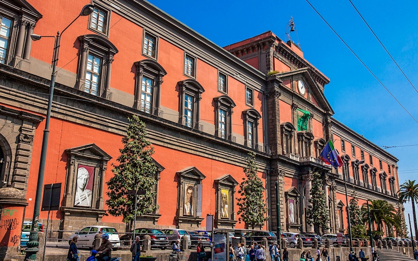 Naples National Archaeological Museum exterior with visitors and parked cars.