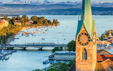 Zurich cityscape with Lake Zurich, boats, and historic clock tower.