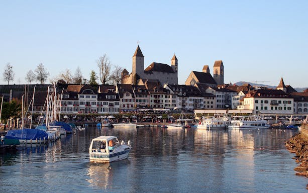 Boats on the water with medieval buildings in Rapperswil, Switzerland, part of Heidiland tour.
