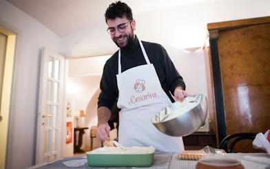 Man preparing dish during private cooking class in Bologna kitchen.