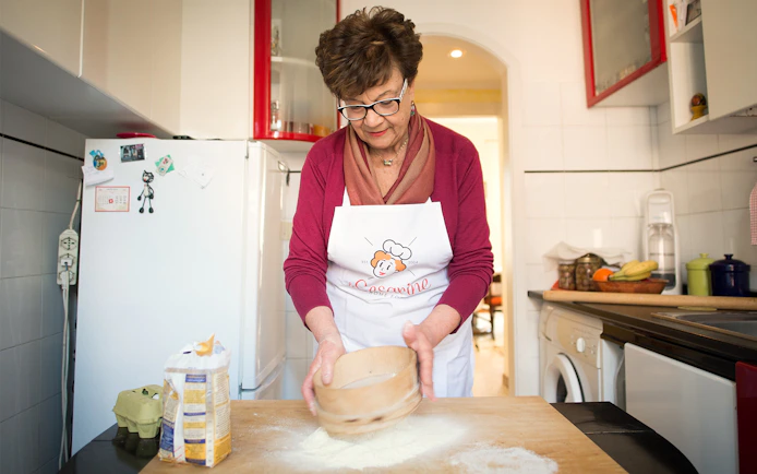 Woman sifting flour during a private cooking class in Rome kitchen.