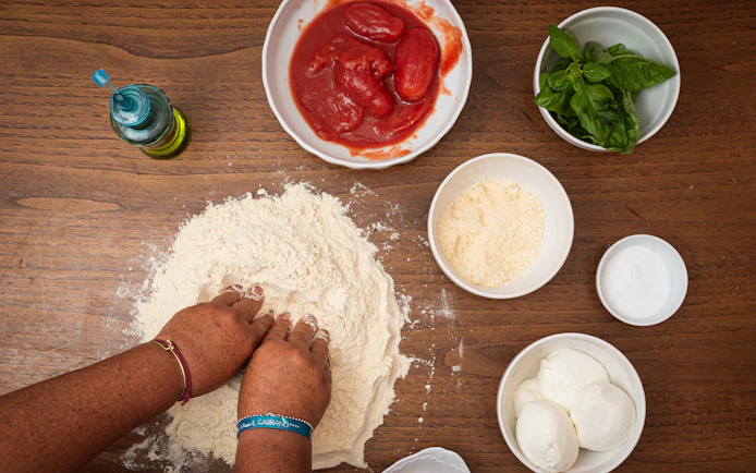 Hands kneading dough with ingredients for a private cooking class in Rome.
