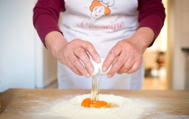 Cracking eggs into flour during a private cooking class in Rome.