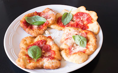 Fried pizza with tomato sauce and basil leaves, featured in a private cooking class in Rome.