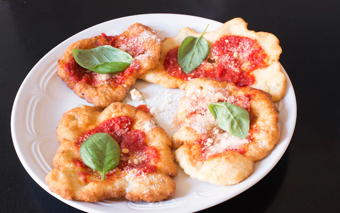 Fried pizza with tomato sauce and basil leaves, featured in a private cooking class in Rome.