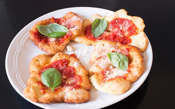 Fried pizza with tomato sauce and basil leaves, featured in a private cooking class in Rome.