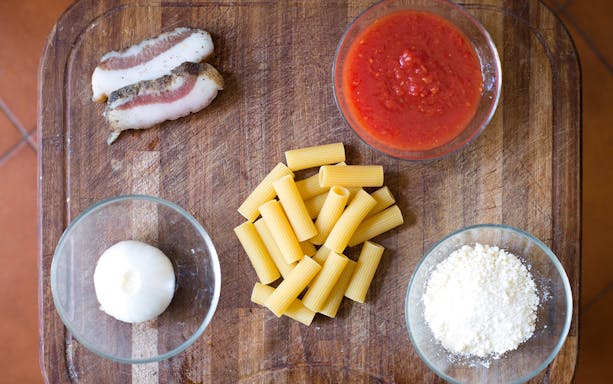 Pasta ingredients for a private cooking class in Rome, including rigatoni, pancetta, tomato sauce, onion, and cheese.