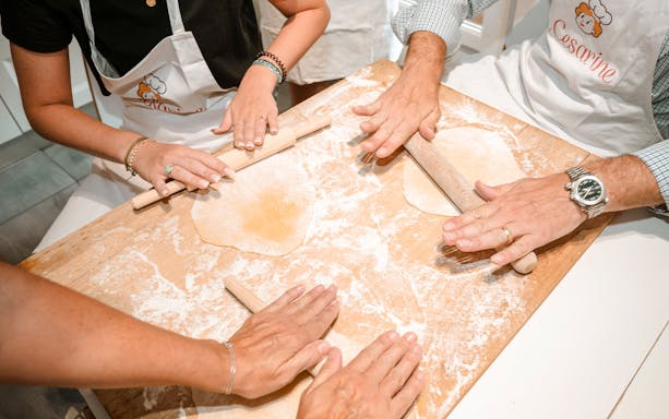 Participants rolling dough in a private cooking class in Milan.