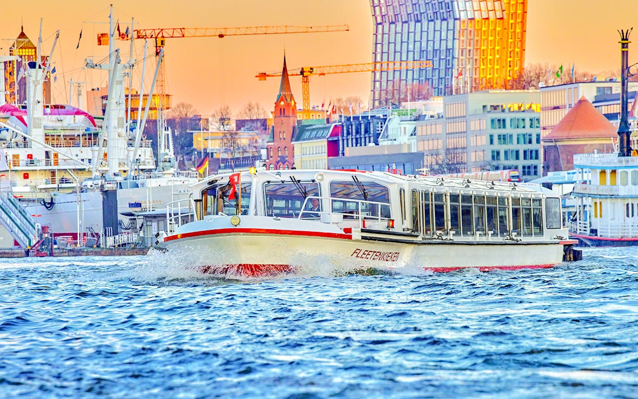 Boat cruising on Alster Lake with Hamburg cityscape in the background.