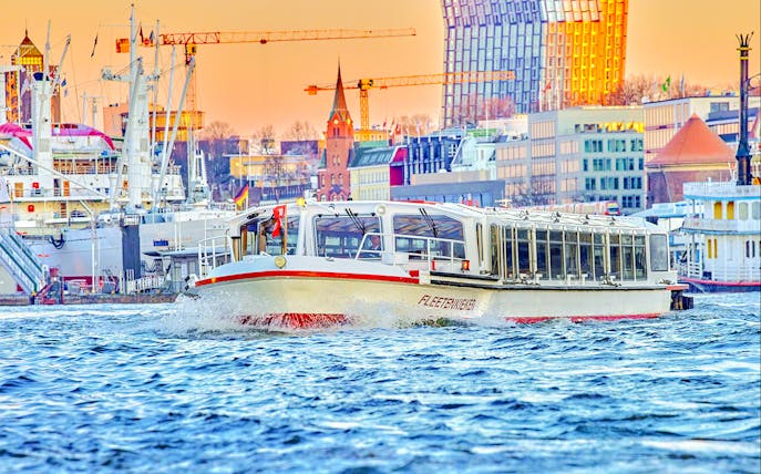 Boat cruising on Alster Lake with Hamburg cityscape in the background.