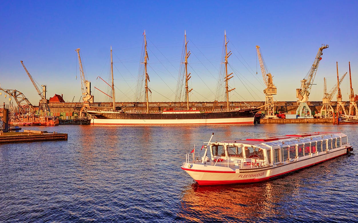 Harbor view with a tour boat and historic ship in Hamburg, Germany.