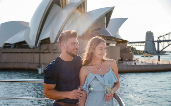 Couple enjoying a harbour cruise with views of the Sydney Opera House and Harbour Bridge.