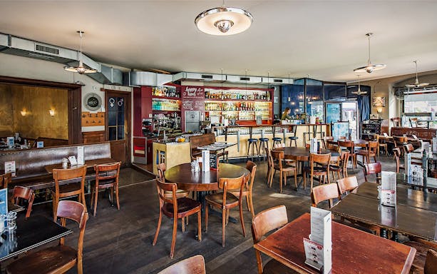 Lausanne café interior with wooden tables and chairs, bar counter, and menu displays.