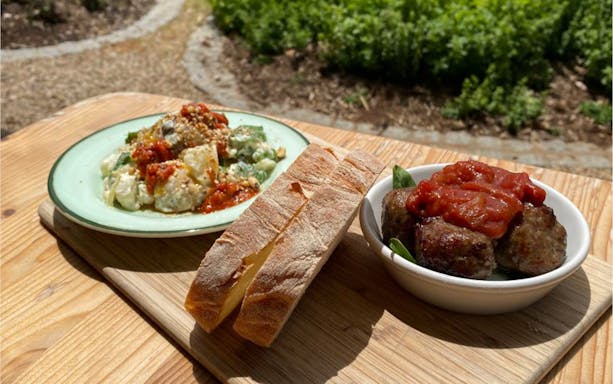Bread and meatballs with sauce on a wooden table at Peninsula Hot Springs tour.