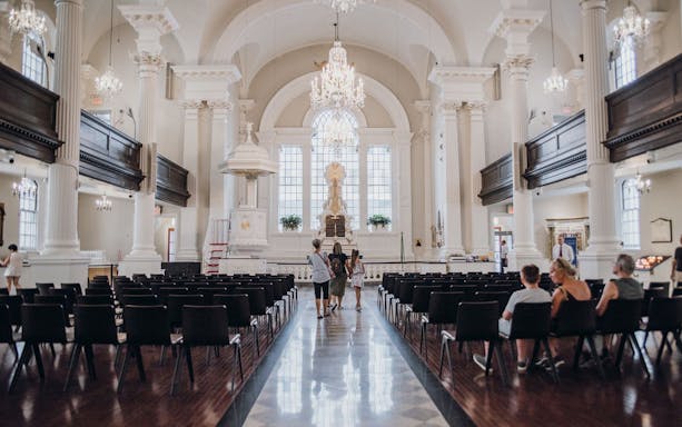 Interior of St. Paul's Chapel with visitors, part of the One World Observatory and 9/11 Memorial Walking Tour.