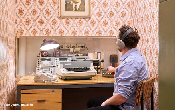 Man using vintage communication equipment at DDR Museum, Berlin.