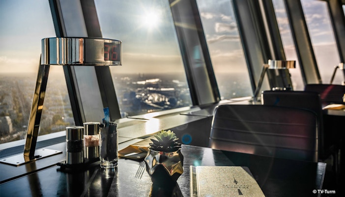 Schwarzer Tisch, auf dem sich ein Salzstreuer, Pfefferstreuer und eine dekortative Pflanze befinden in einem Restaurant mit Ausblick auf die Stadt