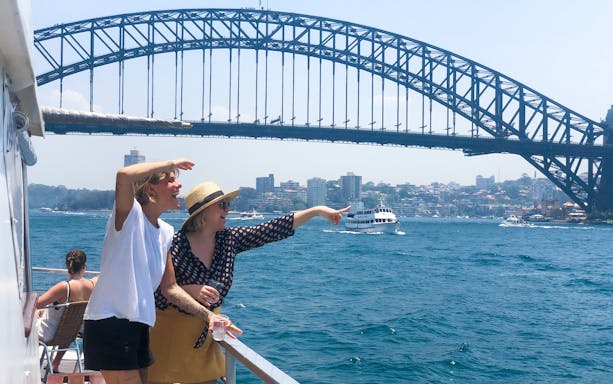 Sydney Harbour cruise with people enjoying views of the Harbour Bridge.