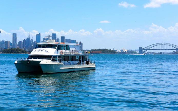 Cruise boat on Sydney Harbour with Opera House and Harbour Bridge in view.
