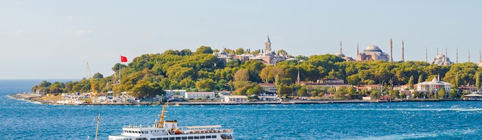 Bosphorus cruise ship passing Istanbul's historic skyline with Hagia Sophia and Topkapi Palace.
