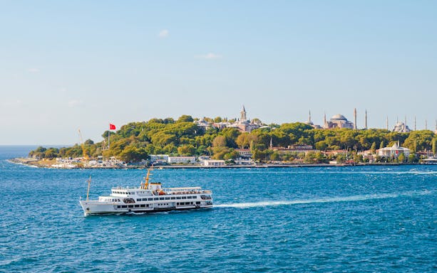 Bosphorus cruise ship passing Istanbul's historic skyline with Hagia Sophia and Topkapi Palace.