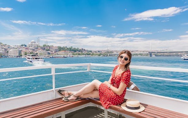 Woman relaxing on a Bosphorus cruise with Istanbul skyline in the background.