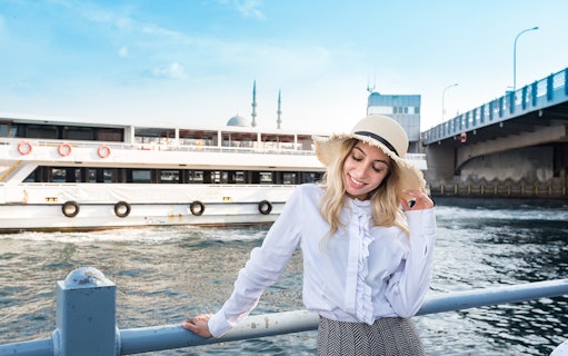 Bosphorus cruise ship near Galata Bridge, Istanbul, with a smiling woman in a hat.